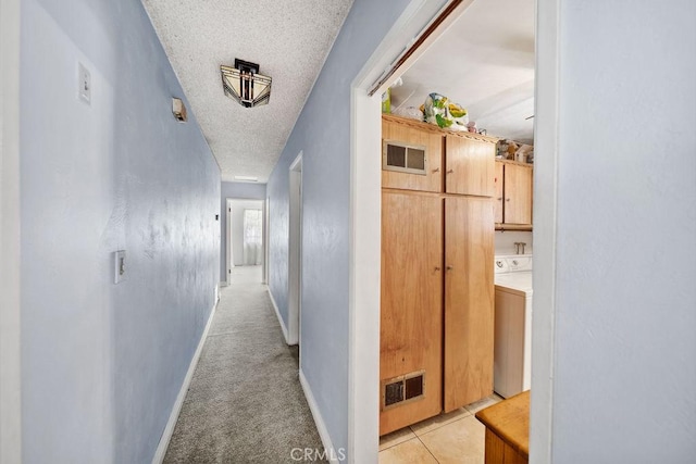 hall featuring washer / clothes dryer, a textured ceiling, baseboards, and visible vents
