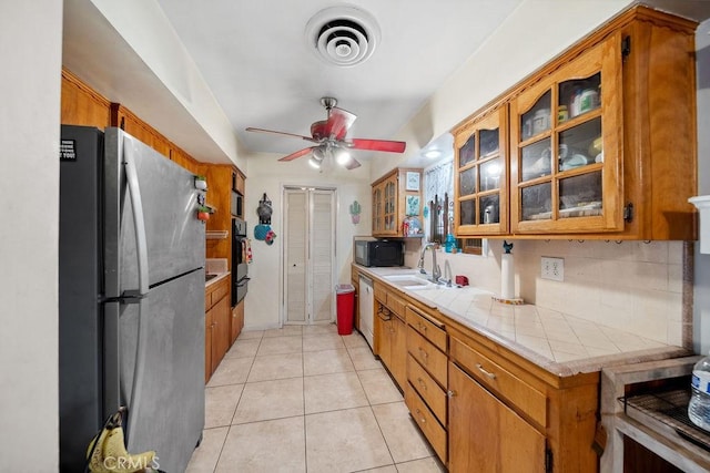 kitchen with black microwave, a sink, freestanding refrigerator, tile countertops, and visible vents