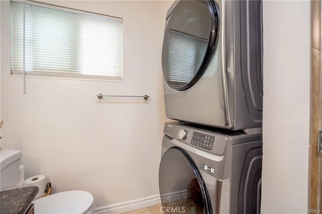 bathroom featuring toilet, baseboards, and stacked washing maching and dryer