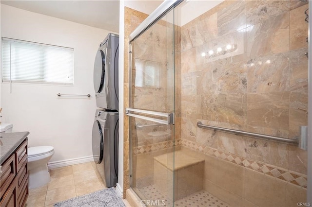 full bath with tile patterned flooring, a shower stall, vanity, toilet, and stacked washer and clothes dryer