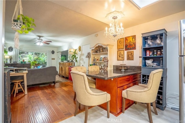 dining space featuring light wood finished floors and ceiling fan with notable chandelier
