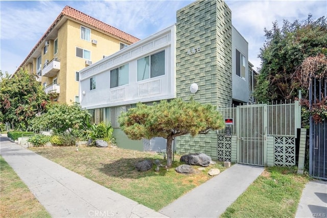 exterior space with a lawn, fence, a gate, and stucco siding