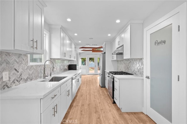 kitchen featuring under cabinet range hood, stainless steel appliances, white cabinetry, and a sink