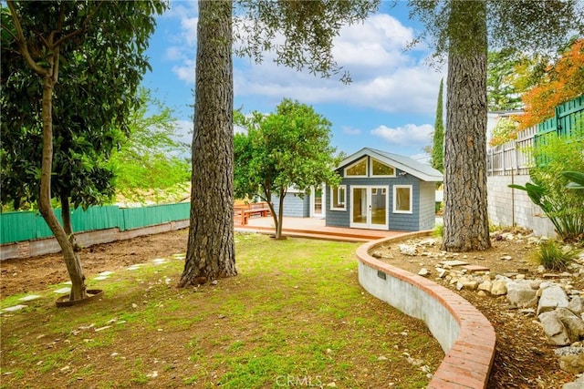 view of yard featuring french doors, a fenced backyard, and a deck