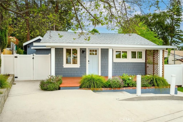 view of front of home featuring a porch, a gate, fence, and a shingled roof