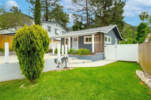 back of house featuring a lawn, fence, and covered porch
