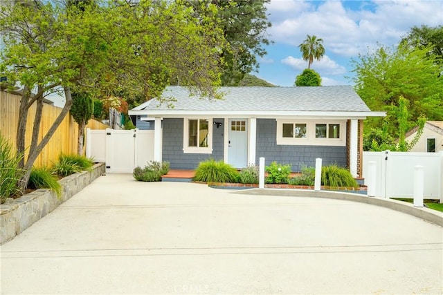 bungalow-style house featuring covered porch, fence, a gate, and roof with shingles