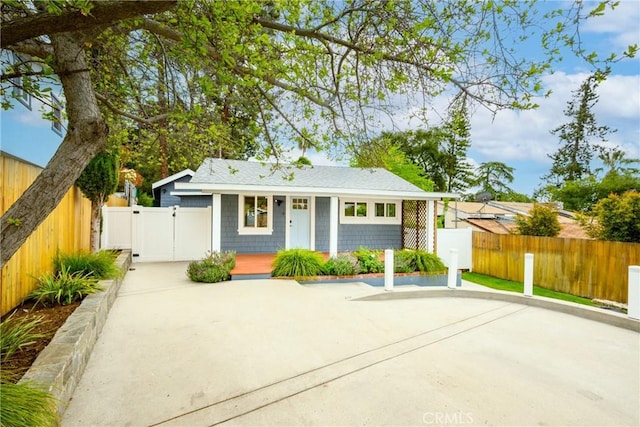 bungalow-style house featuring a porch, fence, a shingled roof, and a gate