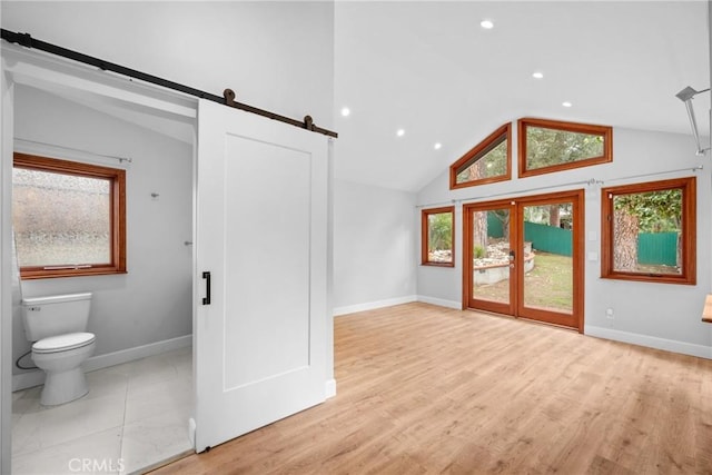 interior space with lofted ceiling, wood finished floors, baseboards, recessed lighting, and a barn door