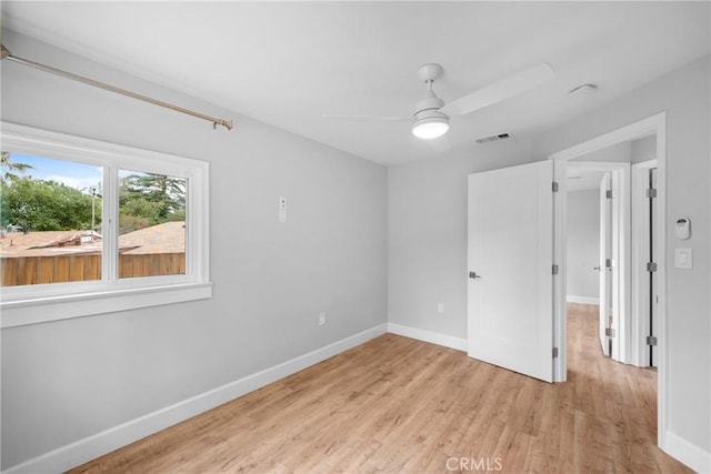 unfurnished room featuring baseboards, light wood finished floors, ceiling fan, and visible vents