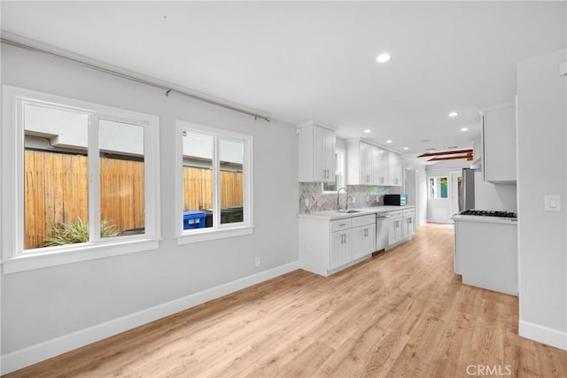 kitchen featuring a sink, baseboards, white cabinets, and stainless steel dishwasher