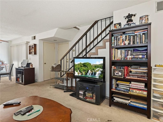 carpeted living room featuring stairs, a textured ceiling, and visible vents