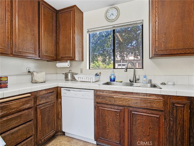 kitchen with white dishwasher, light tile patterned floors, and a sink