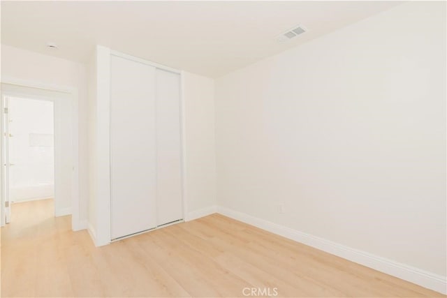 spare room featuring baseboards, visible vents, and light wood-style flooring