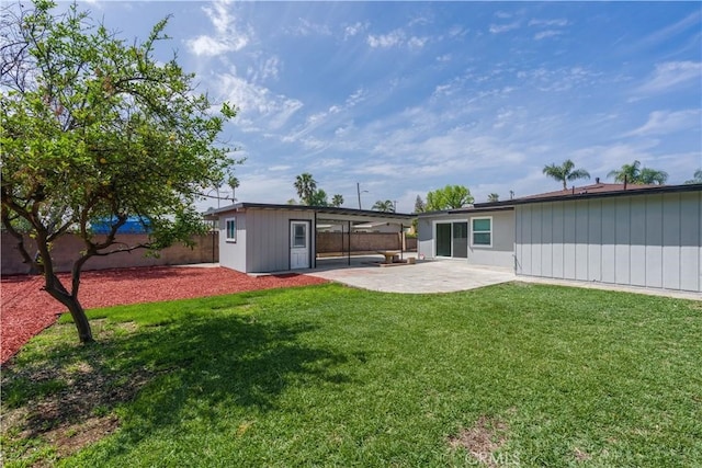 rear view of property featuring a lawn, a patio, an outbuilding, and a fenced backyard