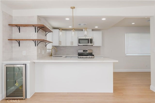 kitchen with light wood-style floors, light countertops, a sink, wine cooler, and stainless steel appliances