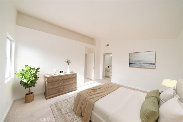 bedroom featuring baseboards, light carpet, ensuite bath, and lofted ceiling