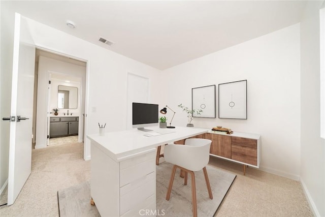 home office featuring a sink, baseboards, light colored carpet, and visible vents