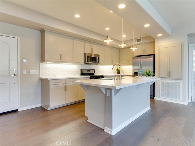 kitchen featuring a sink, appliances with stainless steel finishes, dark wood finished floors, and light countertops