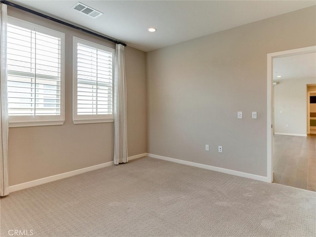 spare room with visible vents, recessed lighting, baseboards, and light carpet