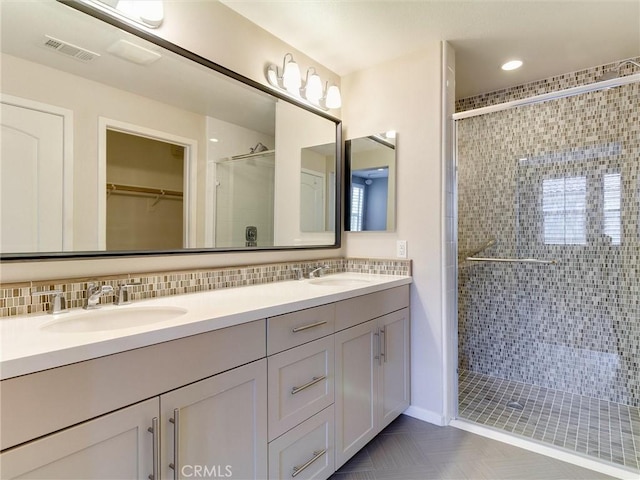 full bathroom featuring visible vents, a sink, double vanity, and a shower stall