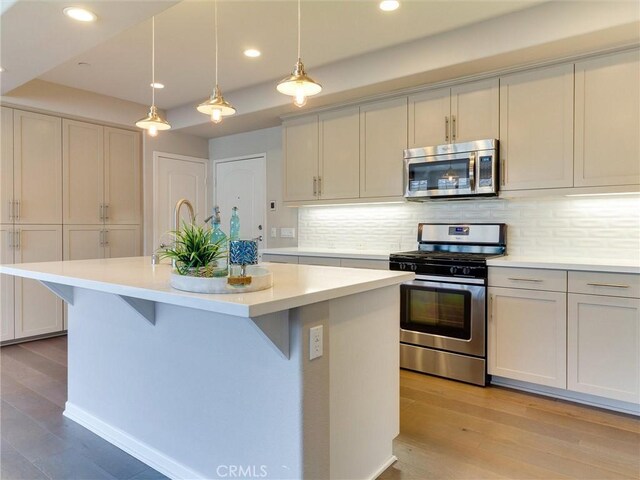 418 Maravilla Ln, Brea, CA 92823 - kitchen with stainless steel appliances, light countertops, a kitchen island with sink, decorative backsplash, and light wood finished floors