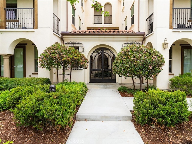 property entrance featuring french doors, a balcony, and stucco siding