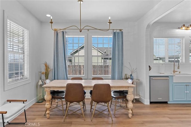 dining area with baseboards, an inviting chandelier, and light wood-type flooring