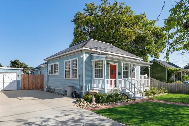 bungalow-style house with fence, concrete driveway, a porch, and a front yard