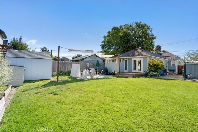 back of property featuring a yard, an outdoor structure, a fenced backyard, and a storage unit