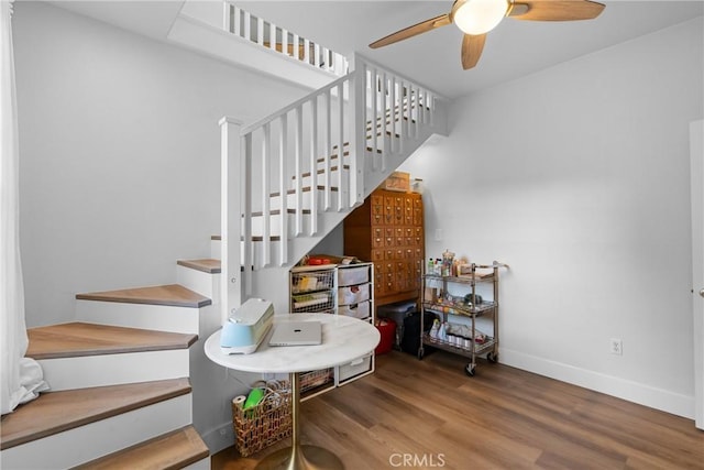 stairway featuring a ceiling fan, baseboards, and wood finished floors