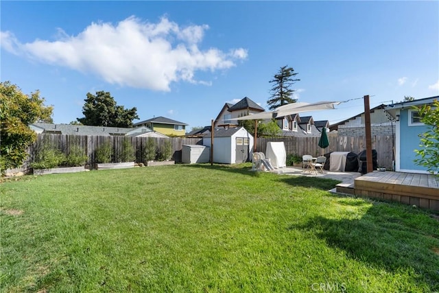 view of yard with a fenced backyard, an outbuilding, a wooden deck, and a storage shed
