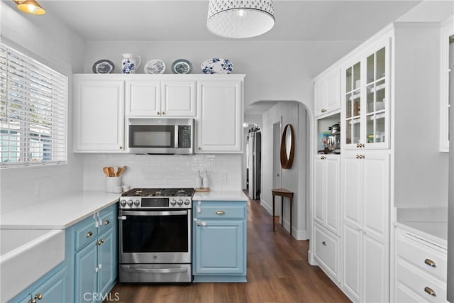 kitchen featuring light countertops, decorative backsplash, stainless steel appliances, and blue cabinets