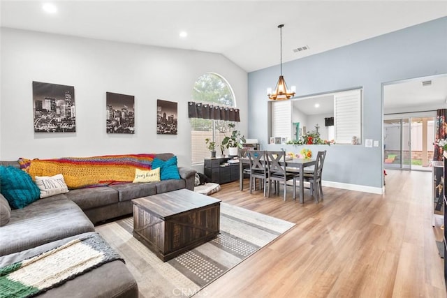 living area featuring vaulted ceiling, light wood finished floors, an inviting chandelier, and visible vents