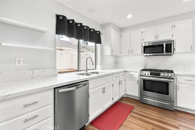 kitchen with white cabinets, stainless steel appliances, open shelves, and a sink