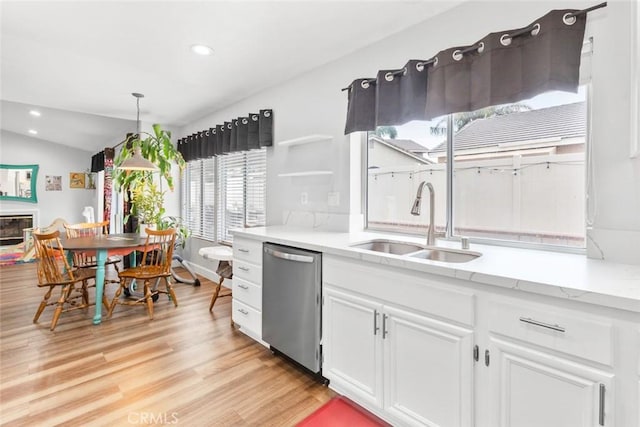 kitchen with stainless steel dishwasher, recessed lighting, white cabinetry, a sink, and light wood finished floors