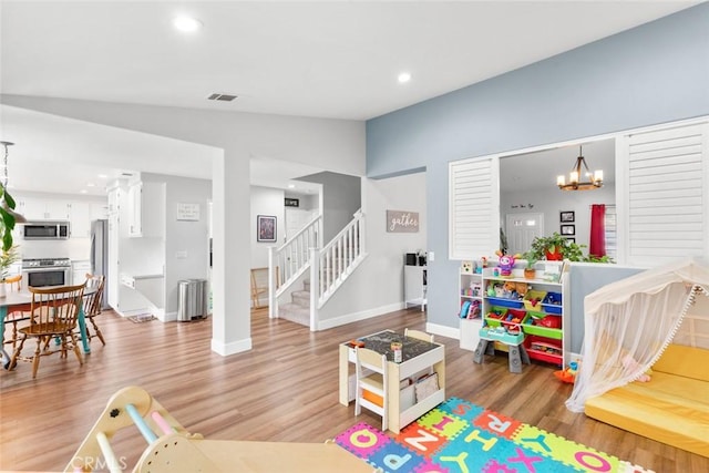 playroom featuring a chandelier, baseboards, vaulted ceiling, and light wood-style flooring