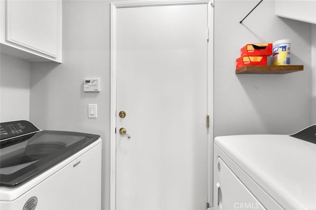 clothes washing area featuring cabinet space and washer and clothes dryer
