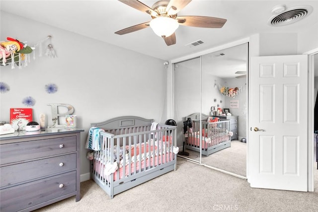 bedroom with carpet floors, a nursery area, visible vents, and a closet