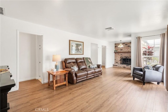 living area with a fireplace, baseboards, visible vents, and light wood-type flooring