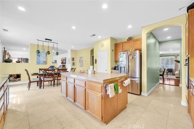 kitchen featuring visible vents, light tile patterned flooring, a kitchen island, arched walkways, and appliances with stainless steel finishes