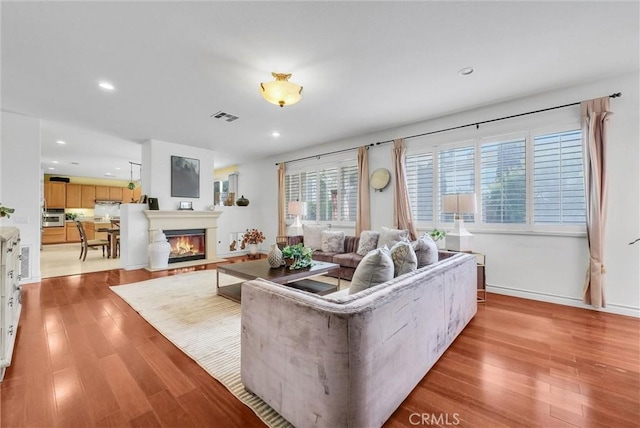 living area with recessed lighting, visible vents, and wood finished floors