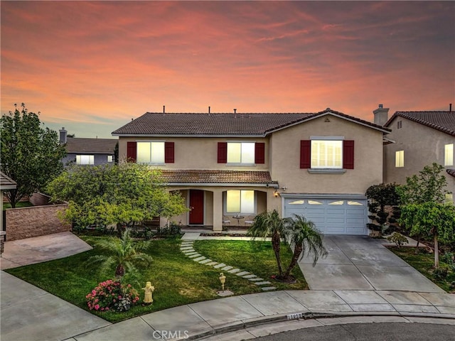 traditional-style house with an attached garage, a tile roof, stucco siding, concrete driveway, and a yard