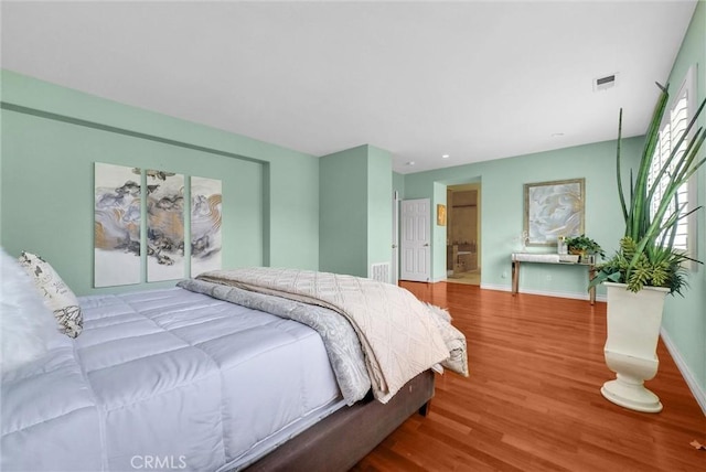 bedroom featuring baseboards, wood finished floors, and visible vents