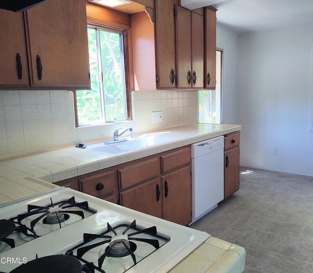 kitchen with cooktop, tasteful backsplash, a sink, and dishwasher