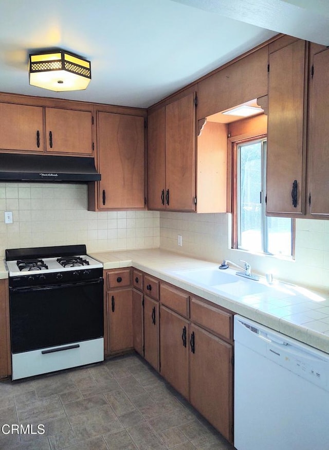 kitchen featuring a sink, dishwasher, decorative backsplash, gas range, and under cabinet range hood