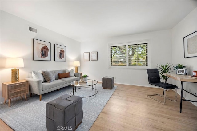 living area with baseboards, visible vents, and wood finished floors
