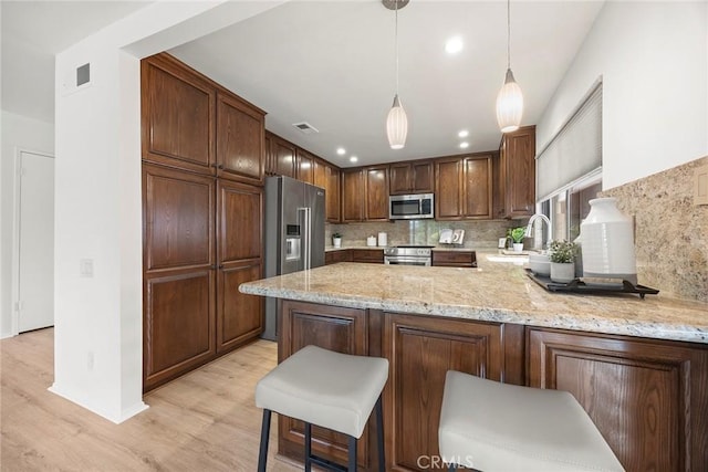kitchen featuring backsplash, visible vents, appliances with stainless steel finishes, and light wood finished floors