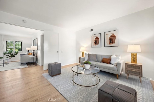 living room with baseboards, visible vents, and light wood finished floors