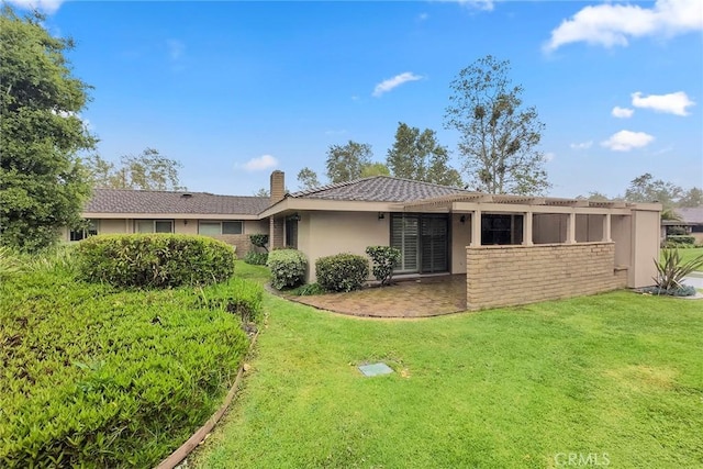 back of property featuring a lawn, stucco siding, and a chimney